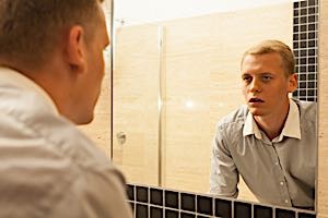 tired sleepy depressed man looks in mirror